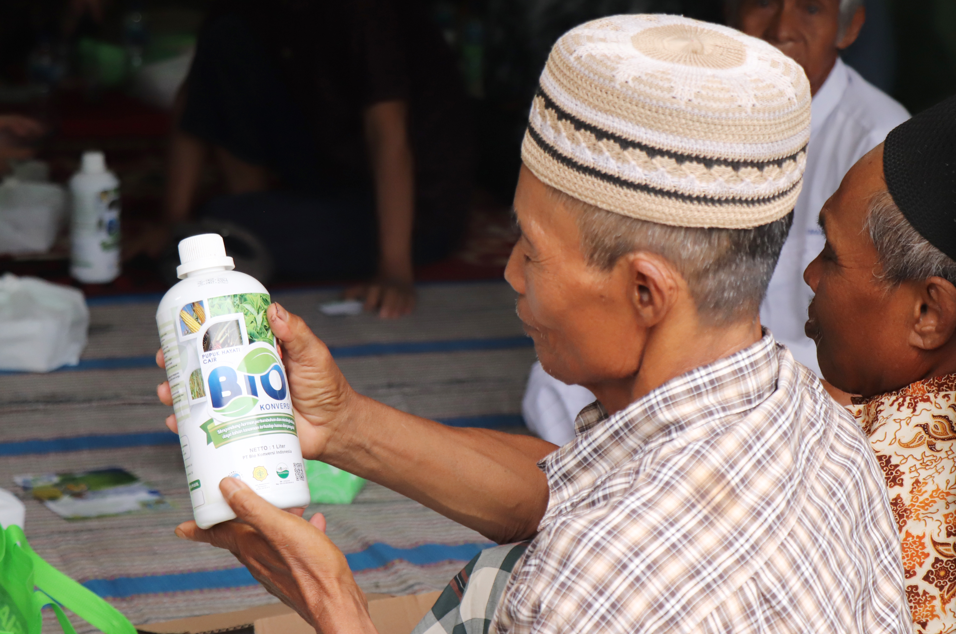 A farmer checking a bottle of fertilizer.